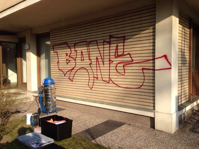 Holzlattenfassade mit großflächigem rotem Graffiti vor der Reinigung, Tornado ACS 35 steht bereit