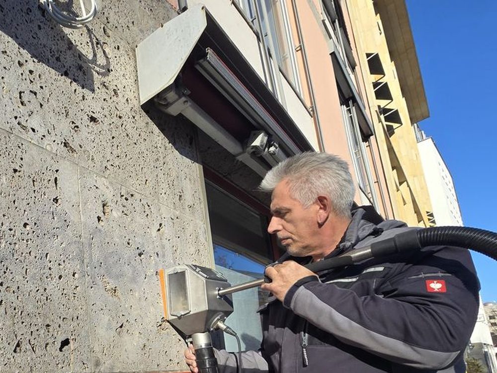 Mitarbeiter von Wandklar München entfernt mit der Lanze des Tornado ACS Farbe von einer porigen Betonfassade