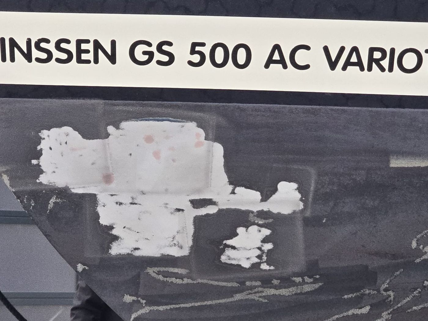 Antifouling wird vom Rumpf einer Yacht abgetragen, die behandelten Stellen heben sich hell vom dunklen Rumpf ab